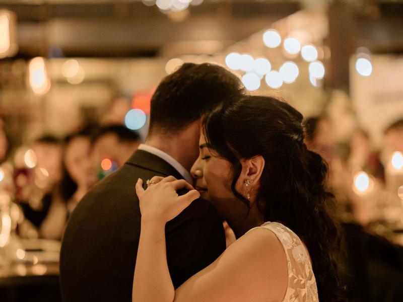 Newlyweds sharing their first dance under warm lights