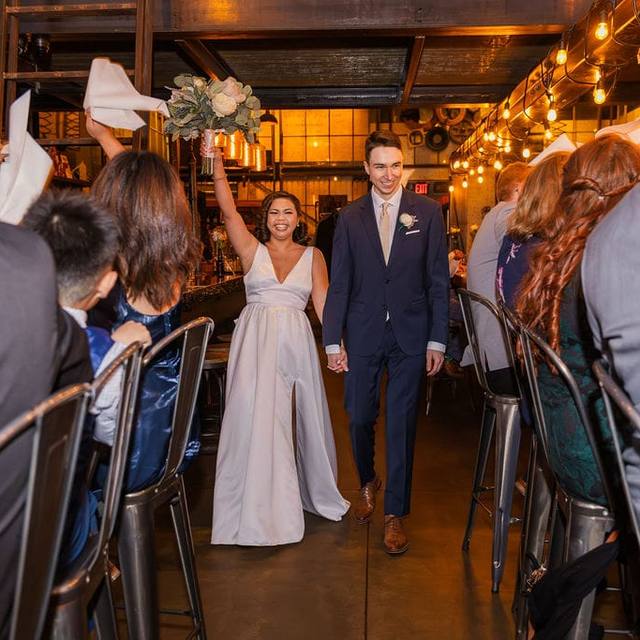 Newlyweds walking in to cheers from their guests